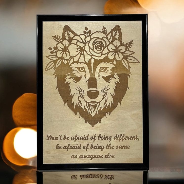 Framed artwork of a wolf with floral crown and motivational quote on a blurred lights background