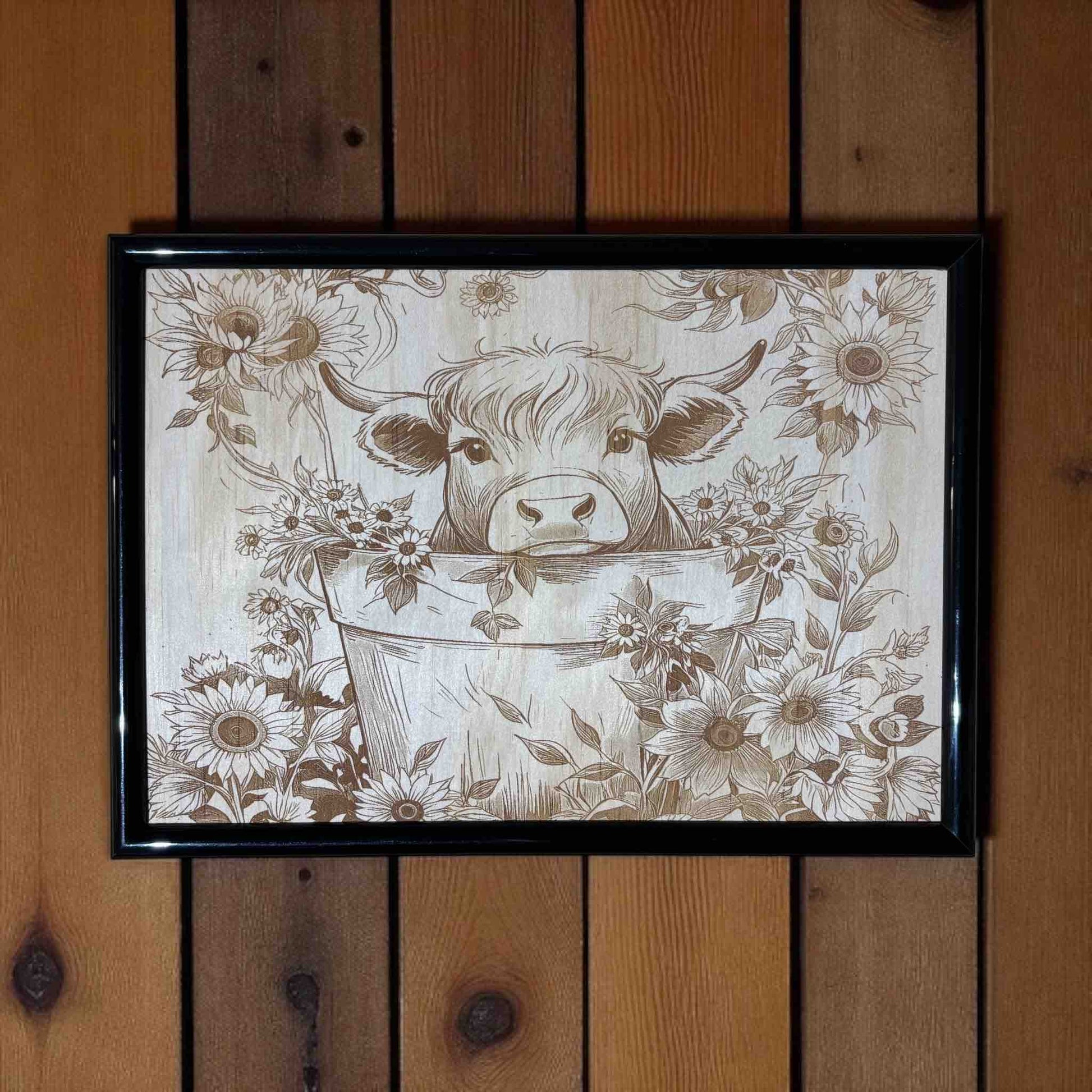 Framed artwork of a cow in a bucket with floral patterns on a wooden wall.