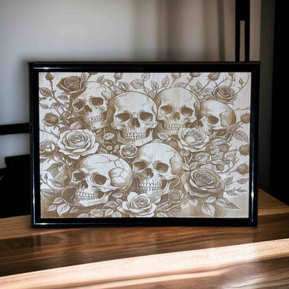 Framed artwork with skulls and roses on a wooden surface