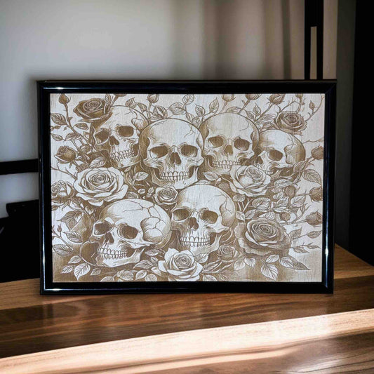 Framed artwork with skulls and roses on a wooden surface
