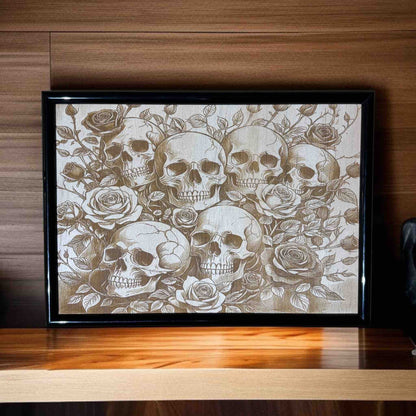 Framed artwork with skulls and roses on a wooden surface