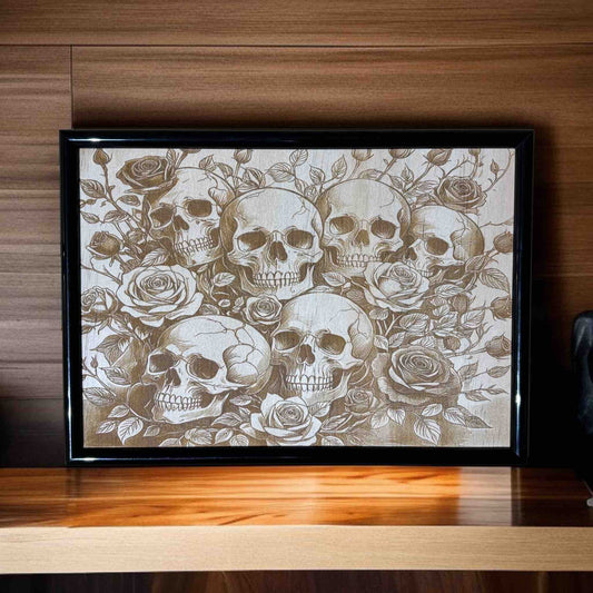Framed artwork with skulls and roses on a wooden surface