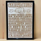 Garage Rules wood engraved art sign displayed on grey workbench, humorous shed and workshop wall decor, Laser Design Creations, Australia.