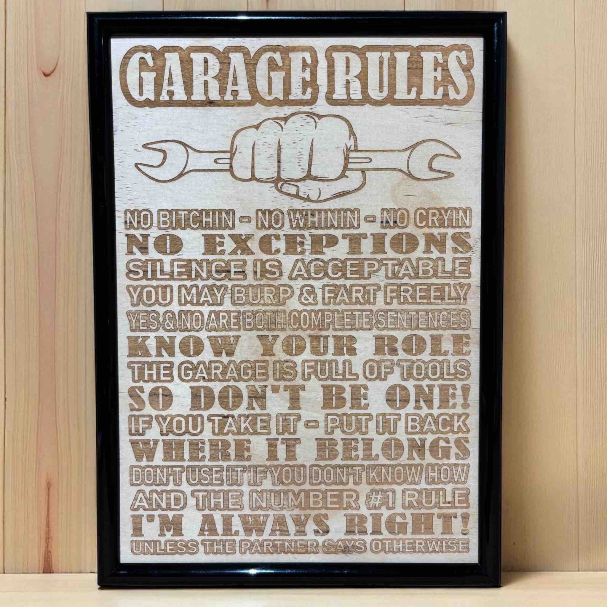 Garage Rules wood engraved art sign displayed on grey workbench, humorous shed and workshop wall decor, Laser Design Creations, Australia.