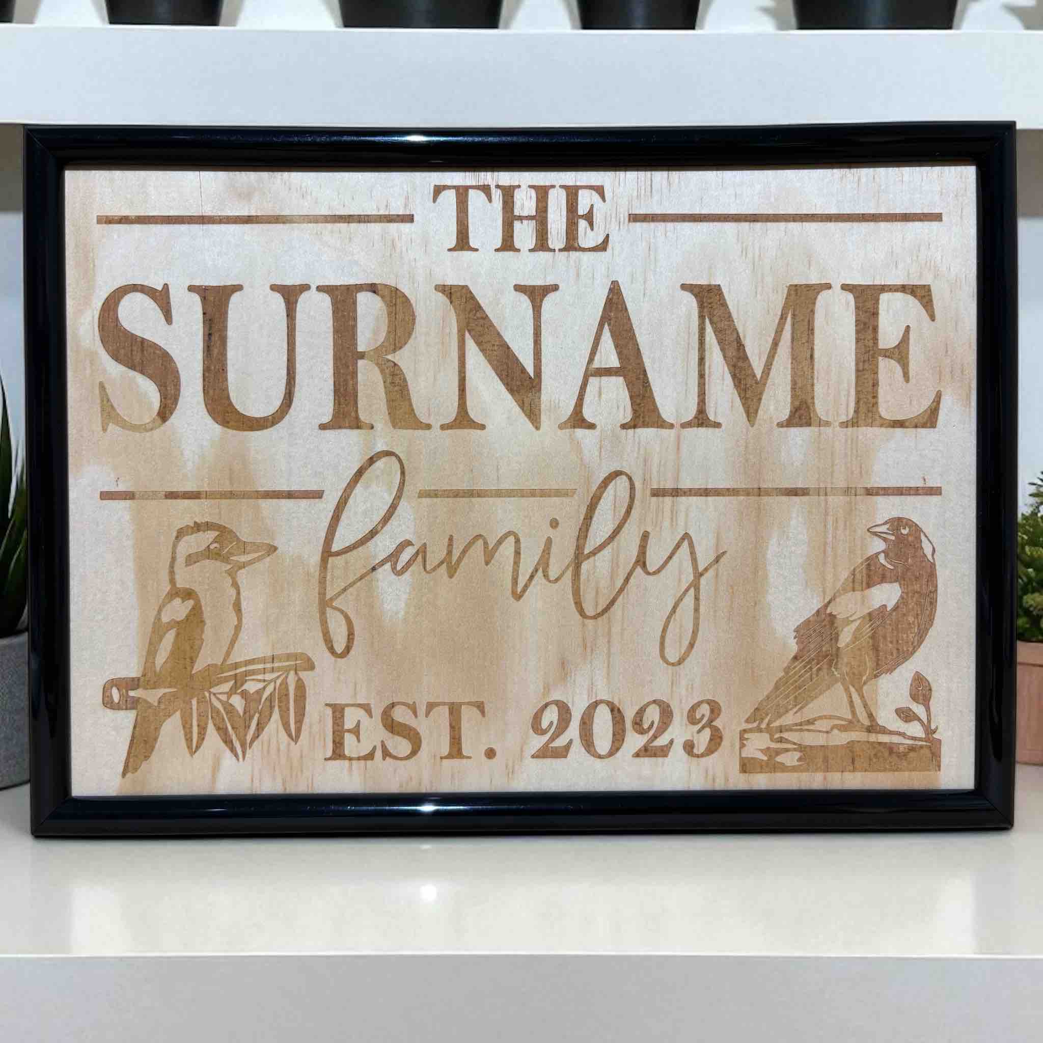 A personalised wood engraved design featuring the text 'The Surname family' with a Kookaburra and Magpie birds, Australian Made. Laser Design Creations