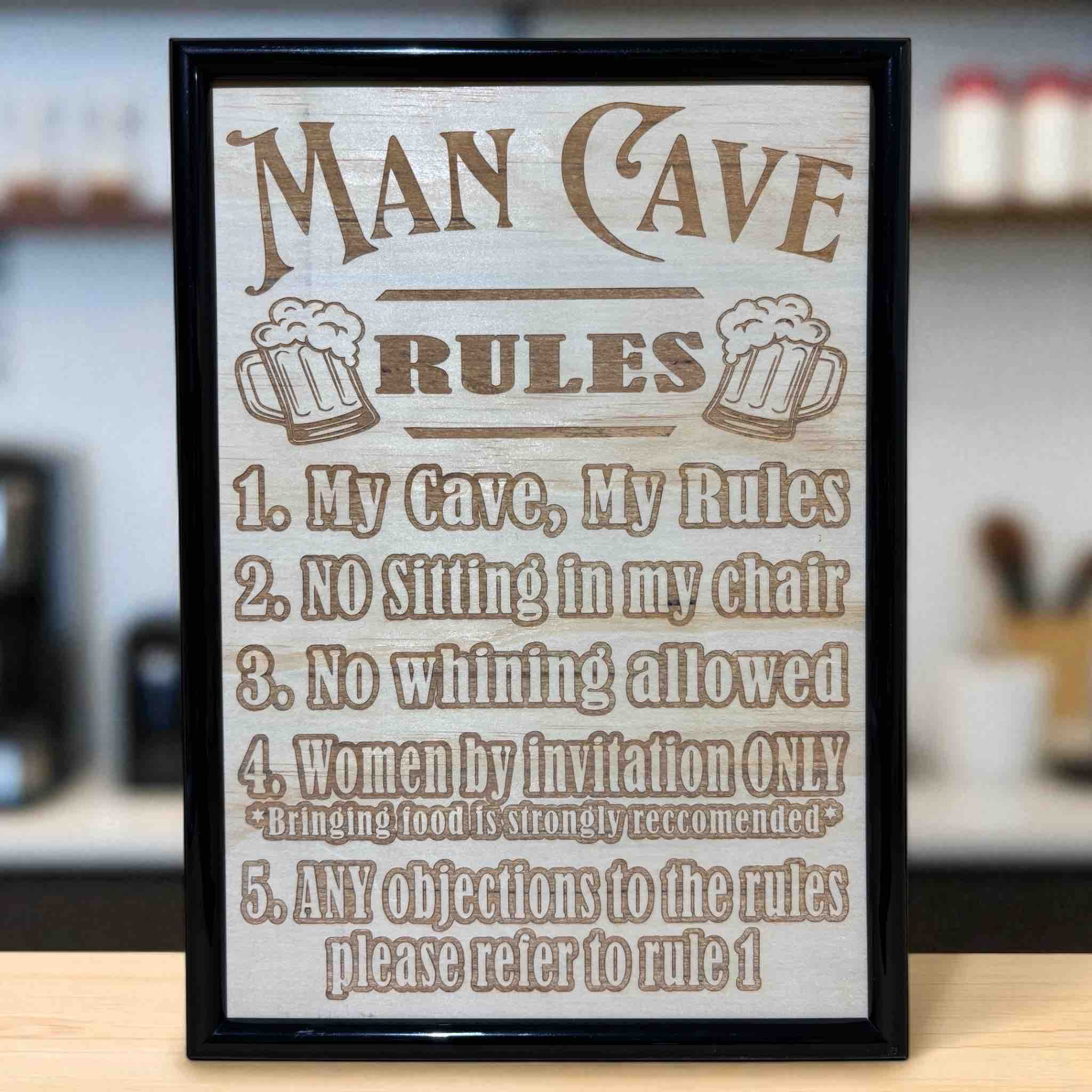 Man Cave Rules wood engraved art sign displayed on bar counter, humorous home bar wall art, Laser Design Creations, Australia.