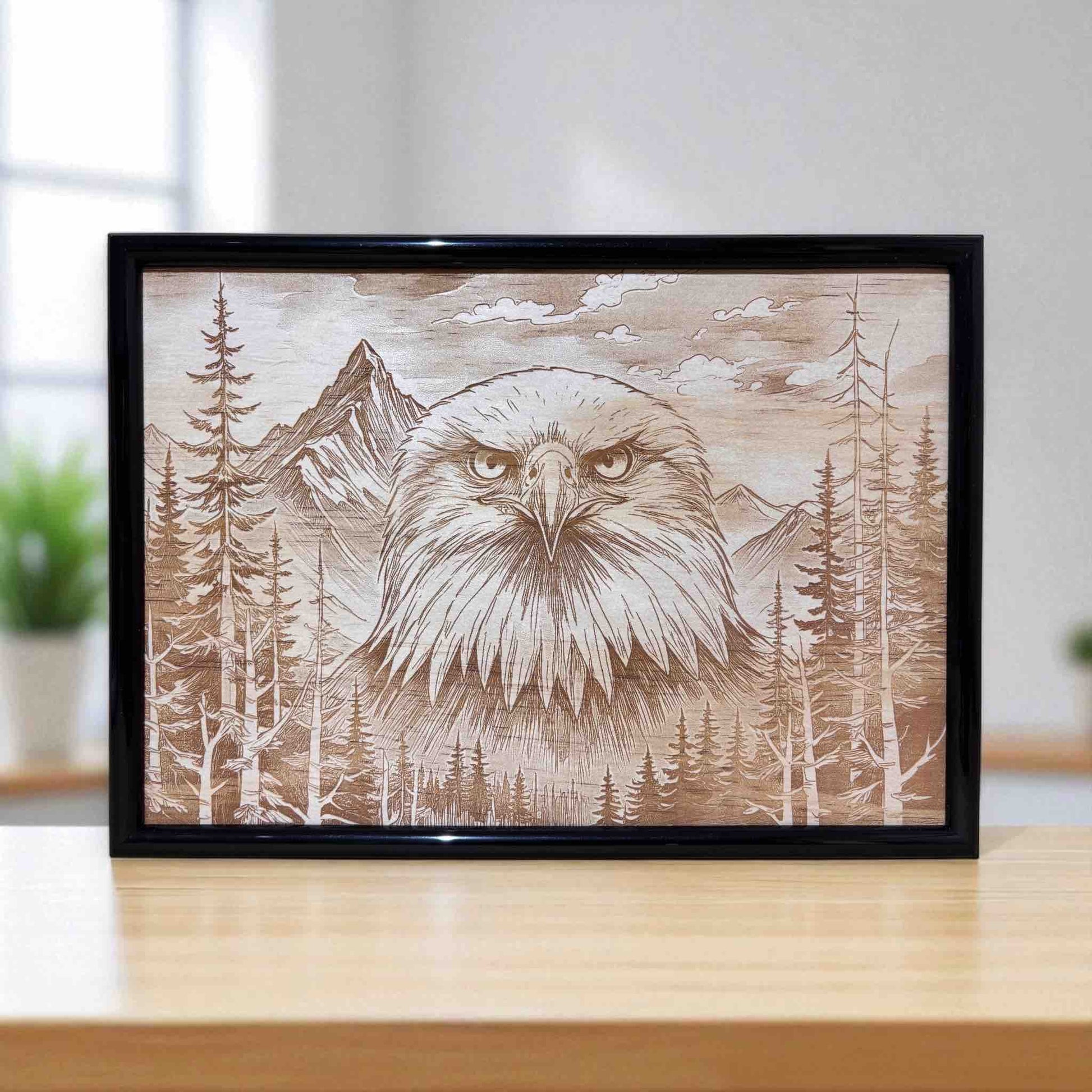 Wood engraved art of a majestic eagle in mountain pines, framed by Laser Design Creations.