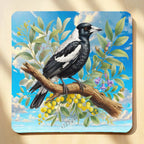Top view of watercolour Australian Magpie neoprene coaster with botanical bird illustration and vibrant yellow wattle flowers, by Laser Design Creations.