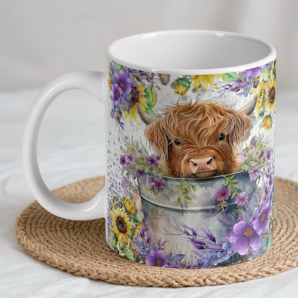 Watercolour Highland Cow Calf ceramic mug by Laser Design Creations, featuring an adorable Highland cow calf in a bucket with sunflowers and purple flowers.