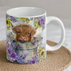 Reverse side of Watercolour Highland Cow Calf ceramic mug, showcasing an adorable Highland cow calf in a bucket with sunflowers and purple flowers by Laser Design Creations.