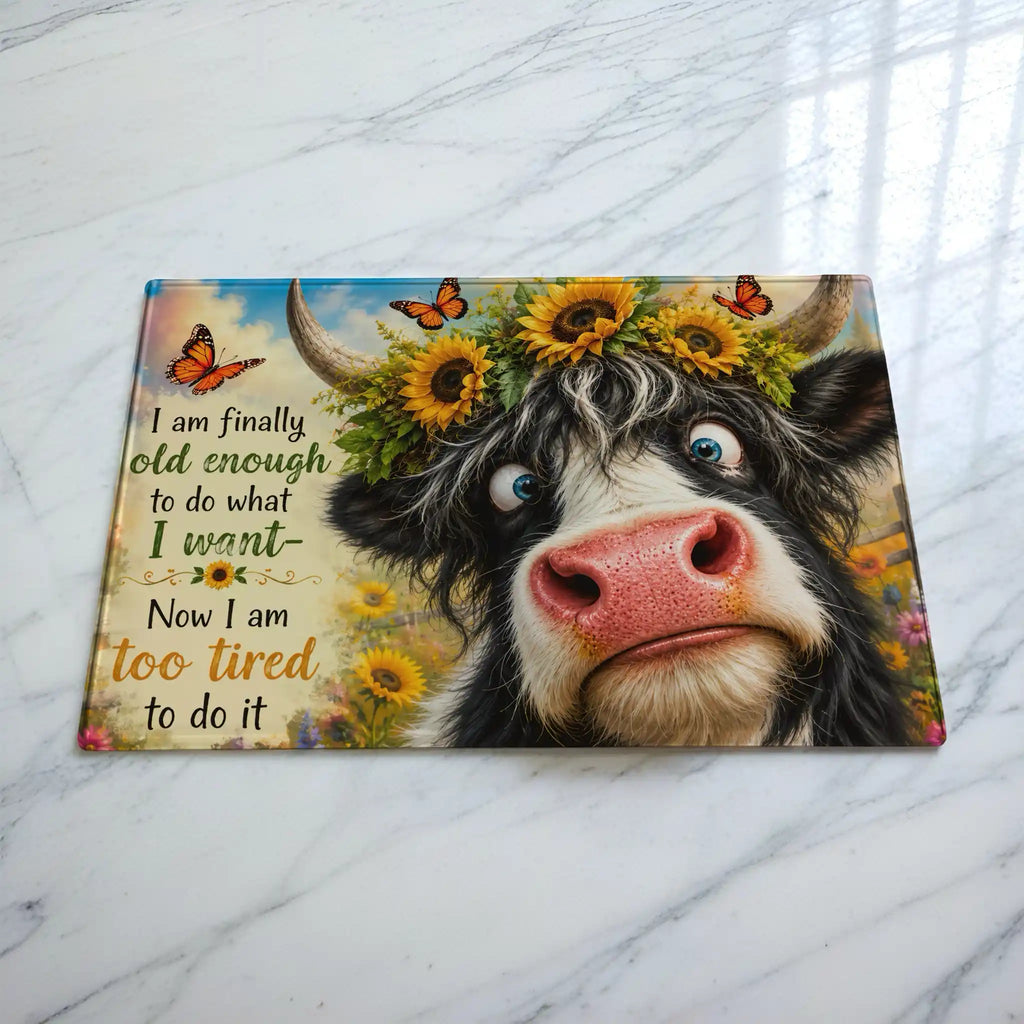 Cheeky Highland Cow chopping board by Laser Design Creations, featuring a funny quote about being too tired on a textured glass background.