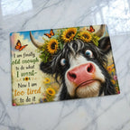 Funny highland cow illustration chopping board from Laser Design Creations featuring the humorous quote, I am finally old enough to do what I want, now I am too tired to do it, on a sleek glass background.