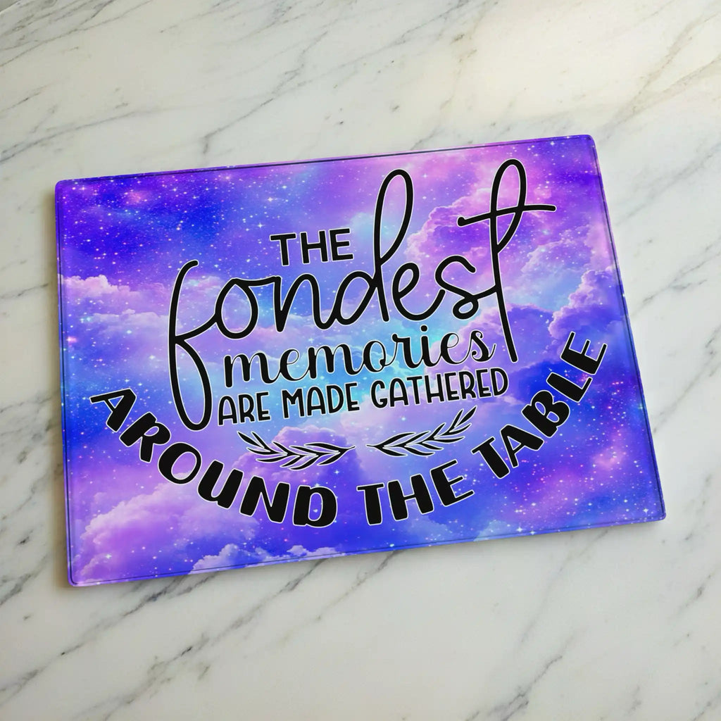 Whimsical starry purple galaxy glass chopping board from Laser Design Creations featuring a beautiful space nebula background and the family quote, THE fondest memories ARE MADE GATHERED AROUND THE TABLE.