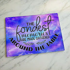 Whimsical starry purple galaxy glass chopping board from Laser Design Creations featuring a beautiful space nebula background and the family quote, THE fondest memories ARE MADE GATHERED AROUND THE TABLE.
