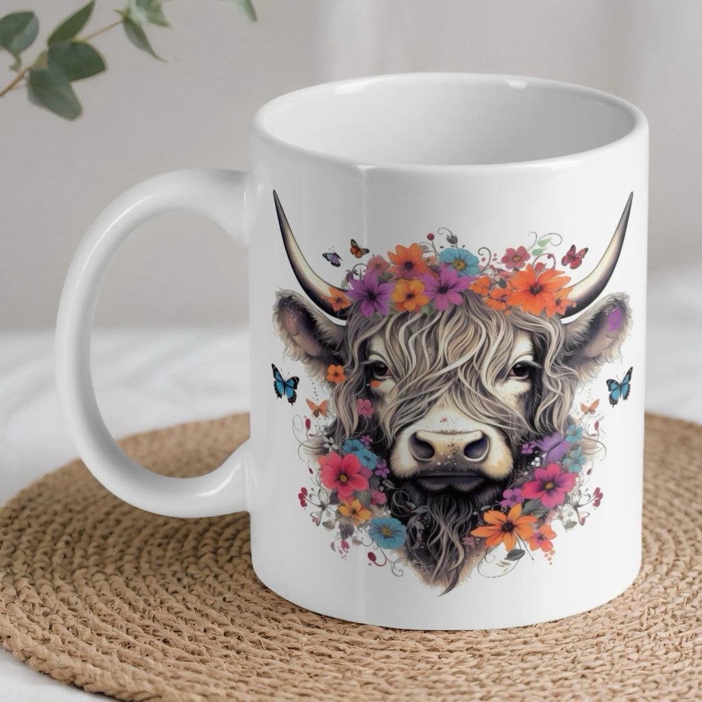 Floral Highland Cow ceramic mug by Laser Design Creations, featuring a whimsical watercolour Highland cow wearing a flower crown with fluttering butterflies.