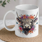 Floral Highland Cow ceramic mug by Laser Design Creations, featuring a whimsical watercolour Highland cow wearing a flower crown with fluttering butterflies.