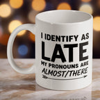 "I Identify As Late" ceramic mug by Laser Design Creations, featuring the witty quote "I Identify As Late My Pronouns Are Almost/There" in a modern typographic style.