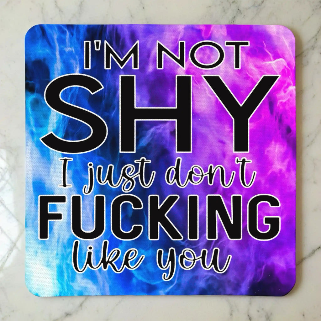 Top view of I'm Not Shy I Don't Like You neoprene coaster with the sarcastic text overlaying a vibrant purple watercolour nebula smoke design, by Laser Design Creations.