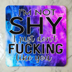 Top view of I'm Not Shy I Don't Like You neoprene coaster with the sarcastic text overlaying a vibrant purple watercolour nebula smoke design, by Laser Design Creations.