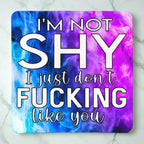 Top view of I'm Not Shy I Don't Like You neoprene coaster with the sarcastic text overlaying a vibrant purple watercolour nebula smoke design, by Laser Design Creations.