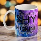 I'm Not Shy I Don't Like You ceramic mug by Laser Design Creations, featuring the humorous quote in bold typography set against a vibrant purple watercolour nebula smoke background.