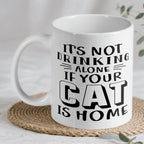 "It's Not Drinking Alone If Your Cat Is Home" ceramic mug by Laser Design Creations, featuring a funny quote for cat lovers.