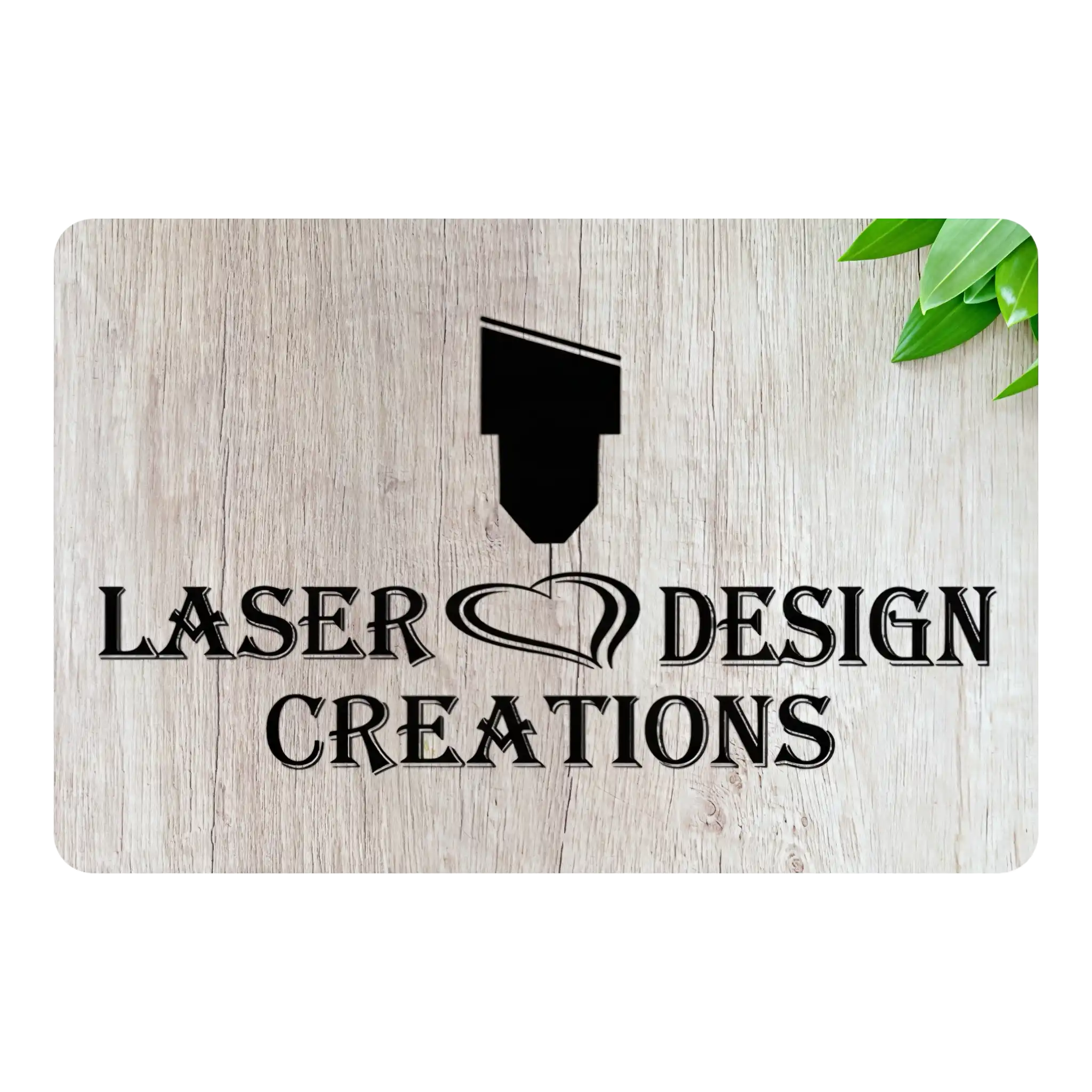 A rectangular sign with a light wood grain texture, featuring the black text 'LASER DESIGN CREATIONS' and a laser pointer graphic. The sign is shown on a white background with a small green leaf in the top right corner.