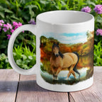 Majestic Wild Mustang ceramic mug by Laser Design Creations, featuring a buckskin horse standing in a river with autumn foliage.