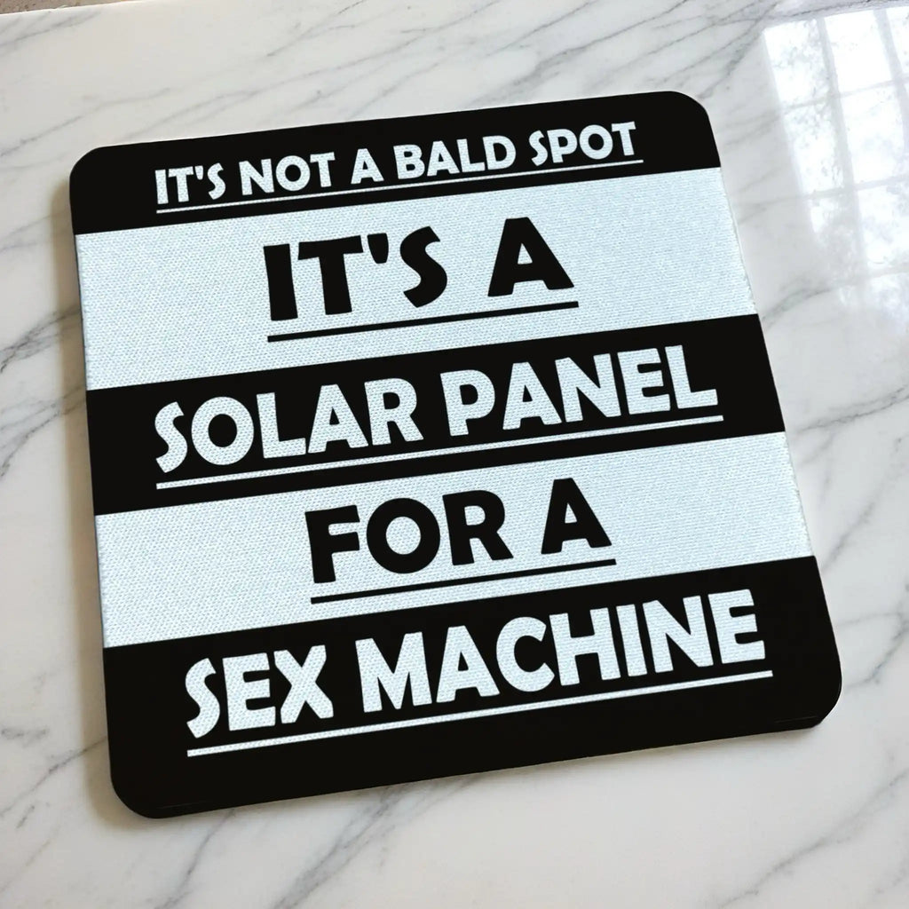 Side view of Not A Bald Spot Solar Panel neoprene coaster with its non-slip black base on a tabletop, by Laser Design Creations.