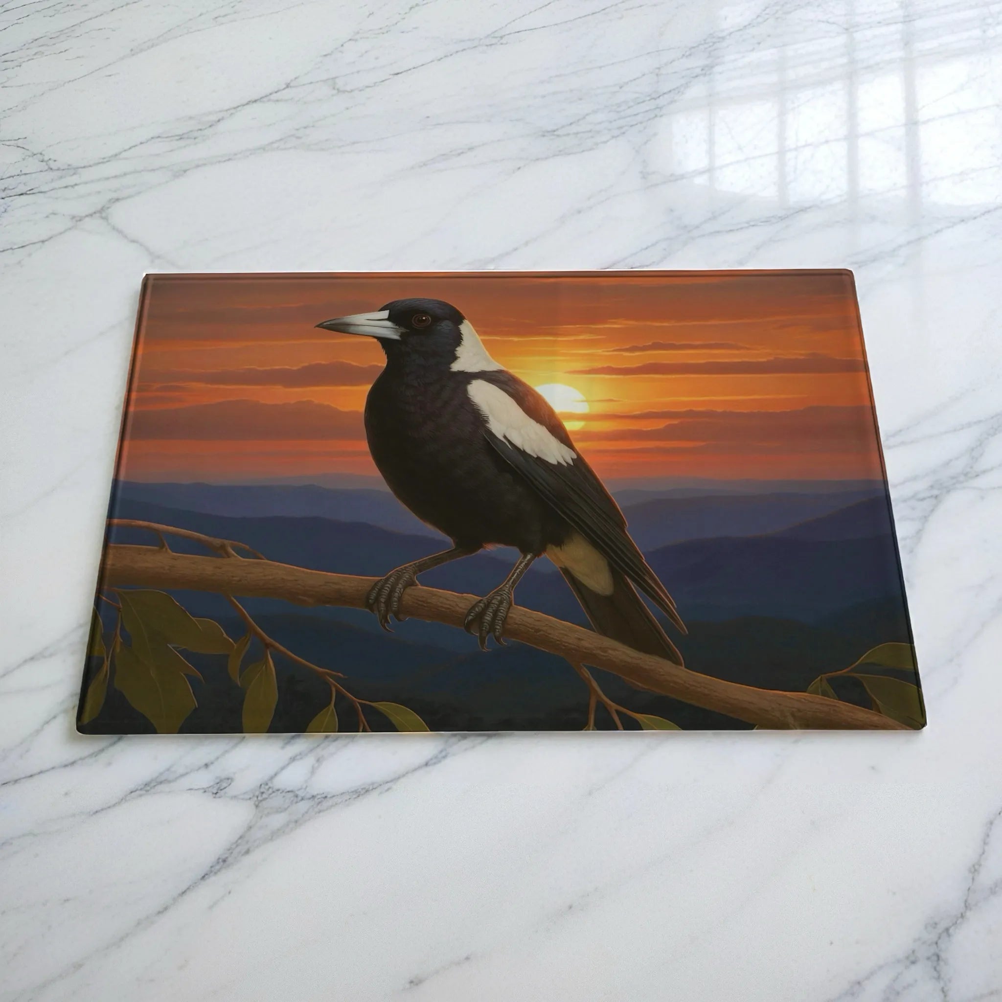 Sunset magpie on branch chopping board by Laser Design Creations, featuring a native Australian bird perched on a tree branch with a scenic mountain sunset in the background.