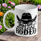 "This ain't my first rodeo" ceramic mug by Laser Design Creations, featuring a funny quote and a cowboy hat.
