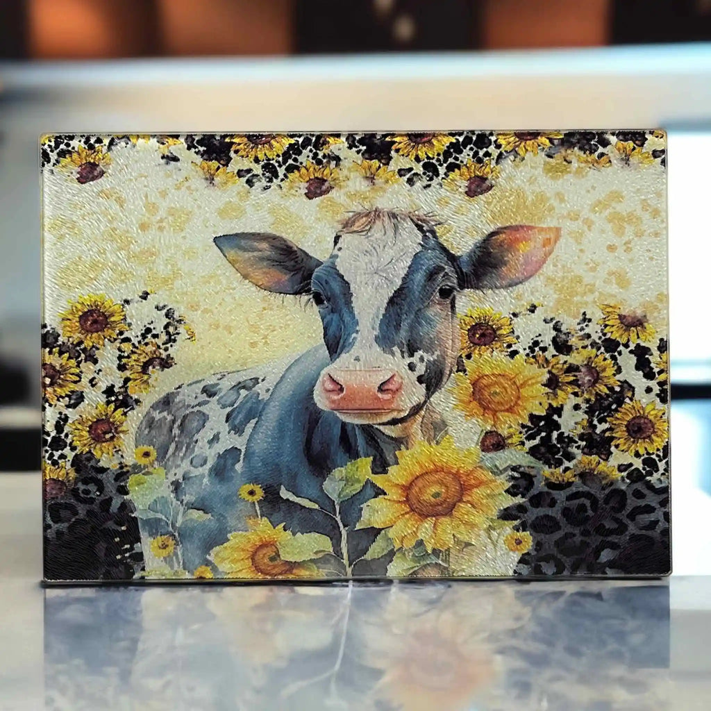 A watercolour cow with bright sunflowers and a leopard print pattern on a glass chopping board from Laser Design Creations