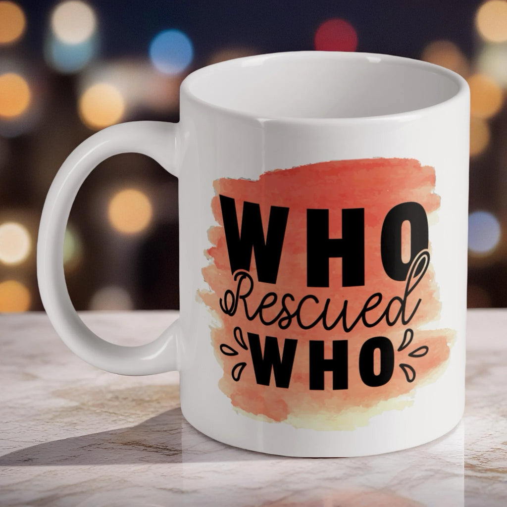 'Who Rescued Who' Quote ceramic mug, showcasing the heartfelt message in black typography over a soft peach watercolour splotch by Laser Design Creations.