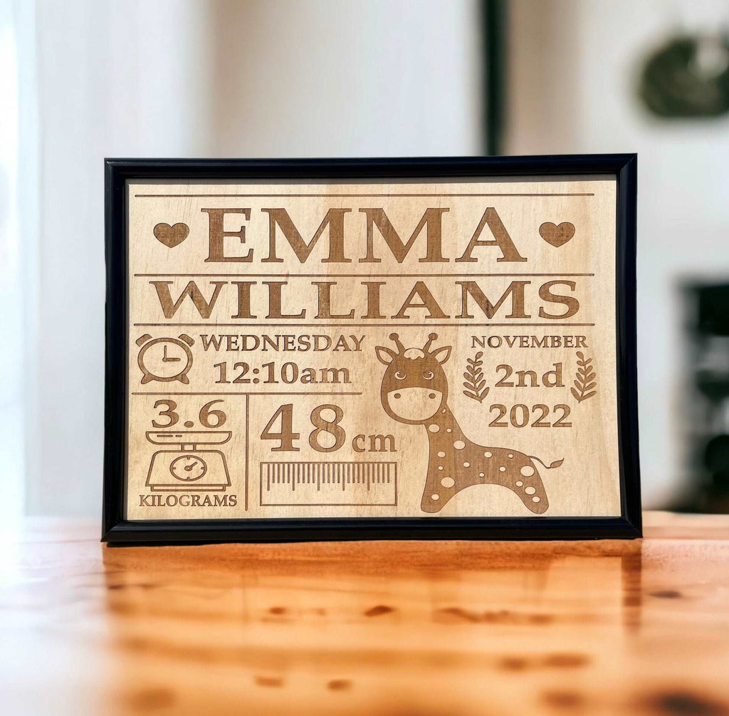 A personalized wooden plaque with engraved baby name birth details, displayed on a wooden desk.