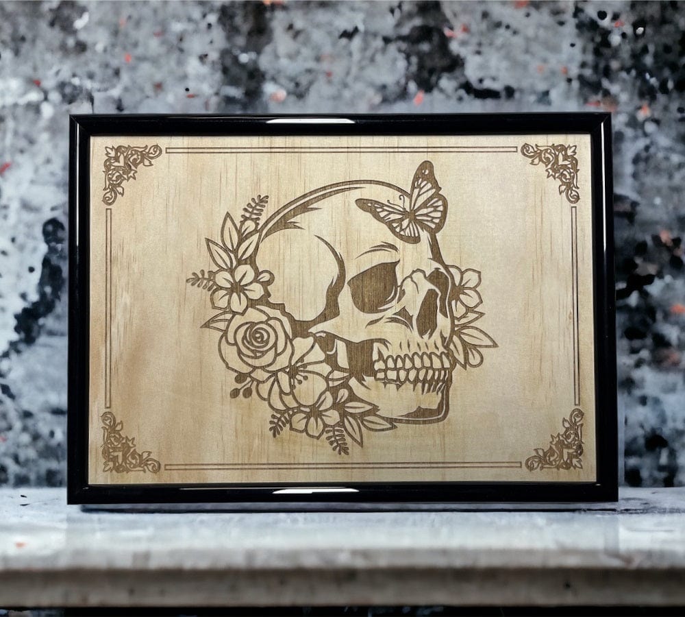 A wood-engraved artwork featuring a floral skull with butterfly designs.